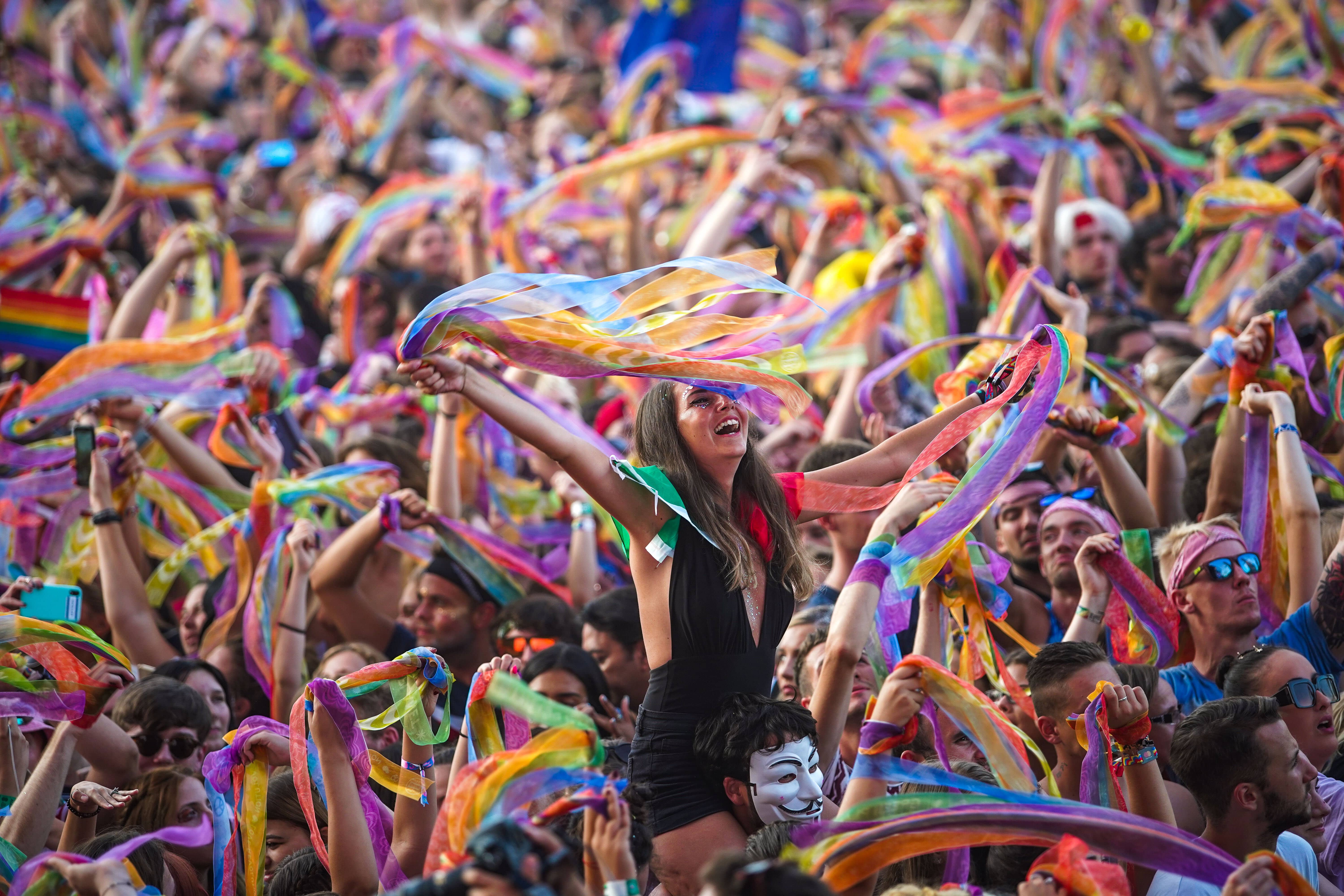 Crowd holding colourful ribbons and girl cheering